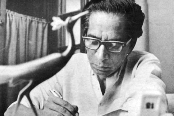 চশমা পরা ঔপন্যাসিক রমাপদ চৌধুরী টেবিলে লিখছেন